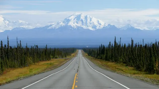 Scenic highway leading toward a snow-capped mountain in Alaska