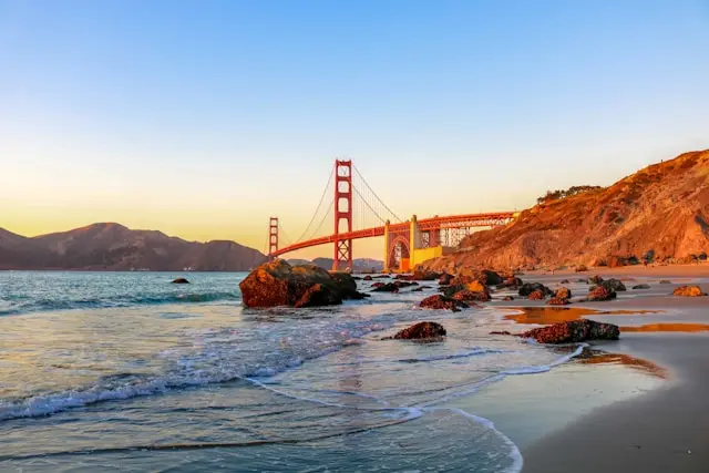Golden Gate Bridge viewed from a rocky San Francisco beach at sunset