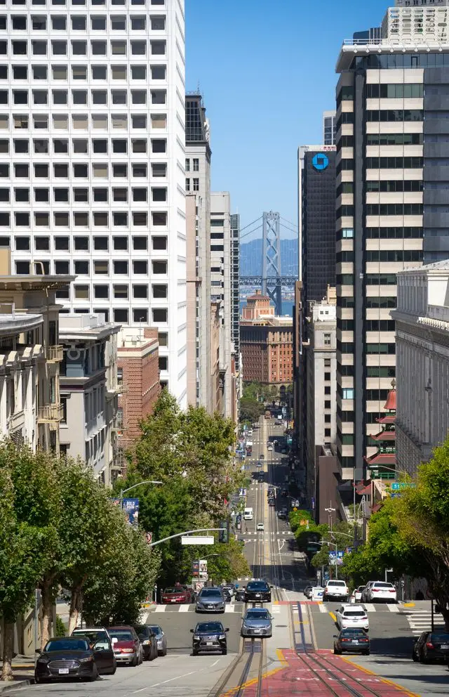 Downtown San Francisco street with cable car tracks and the Bay Bridge in the distance